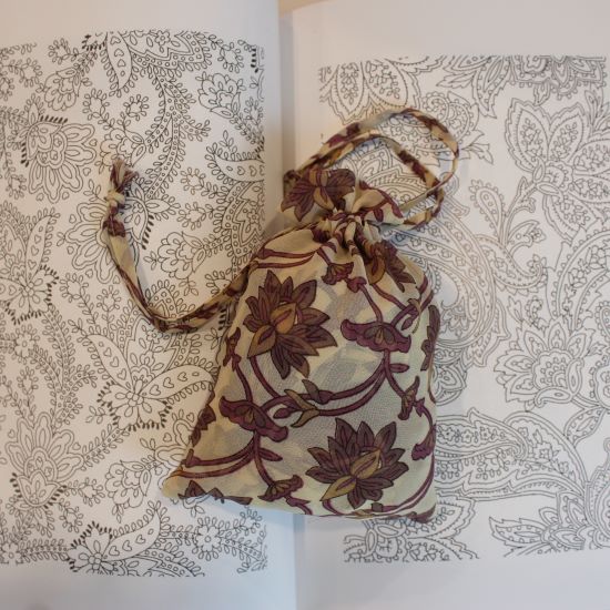 mayil floral magenta scarf on its bag, lying on an open book