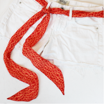orange skinny scarf styled as a belt on white denim shorts