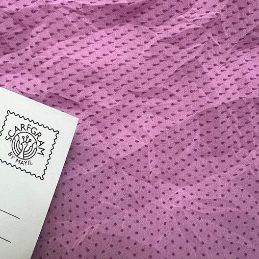 Close-up of pink fabric with a visible brand label.